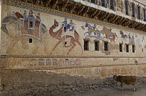 Traditional paintings on wall of Havelis (merchant's house) with cow standing in stree, Ratannagar, Rajasthan, India
