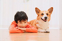 Portrait of young boy with Welsh Corgi lying down