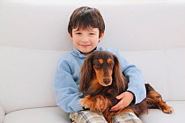 Portrait of young boy sitting with Longhaired Dachshund on his lap