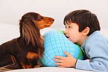 Portrait of young boy playing with Longhaired Dachshund, face to face