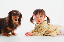 Portrait of young girl lying down with longhaired Dachshund