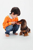 Portrait of young boy feeding a long-haired Dachshund