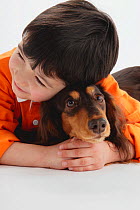 Portrait of young boy hugging a long-haired Dachshund