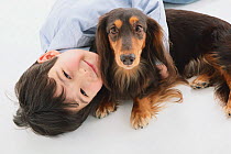 Portrait of young boy lying down with a longhaired Dachshund