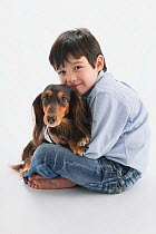 Portrait of young boy sitting down with a longhaired Dachshund on his lap
