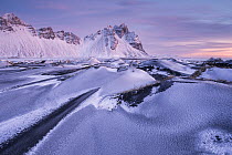 Vestrahorn mountain and sand dunes covered in snow at sunrise, Stokksnes Peninsula, Iceland. January, 2024.
