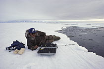 Inuit researcher using hydrophone to record Narwhal (Monodon monoceros) vocalizations under the arctic ice, Baffin Island, Canada