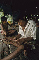 Embera Choco Indian making a blowgun for hunting with poisoned darts, Colombia