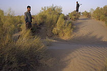 Trip coordinator, Jahangiri, looks for Lizards with militia guard nearby, Zabul, Iran