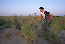 Hadi Fahini dashes after lizard with a fishing pole, near Zabul, Iran