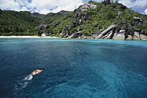 Swimmer and coral sand beaches with unique granite formations, Seychelles