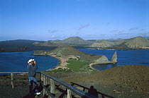 Visitor admiring classic summit view of Pinnacle Rock and volcanic landscape, Bartolome Island, Galapagos Islands, Ecuador