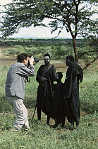 Tourist photographing young Masai tribesmen in typical dress and body paint after circumcision, Tanzania