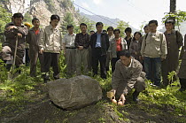 Giant Panda (Ailuropoda melanoleuca) keeper, He Changgui tearfully places Mao Mao's favorite food next to her tombstone after the May 12, 2008 earthquake and landslides, CCRCGP, Wolong, China
