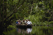 Tourists in dugout canoe in blackwater stream, Yasuni National Park Biosphere Reserve, Amazon rainforest, Ecuador