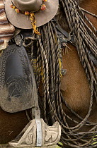 Close up detail of a chagra or cowboy's hat with Mountain roses in the band, lasso, and decoratively carved wooden stirrup, Hacienda Yanahurco, Andes Mountains, Ecuador