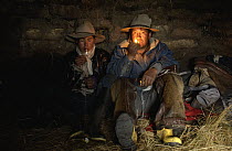 Chagra cowboys smoking and relaxing in camp at a hacienda during the annual overnight cattle round-up, Andes Mountains, Ecuador