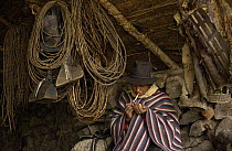 Chagra cowboy smoking among lassos, saddles and tack at a hacienda in the Andes Mountains during the annual cattle round-up, Ecuador