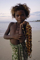 Child selling necklaces on the beach made from seeds and shells found locally, Mangily, near Ifaty, southwestern Madagascar