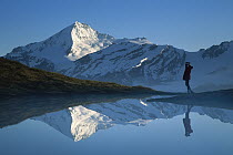 Mt Aspiring and hiker reflected in lake at dawn, Cascade Saddle, Mt Aspiring National Park, New Zealand