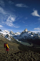 Hiker on Loma Plieque Tumbado admiring the view of Cerro Torre, left, and Fitzroy, Los Glaciares National Park, Patagonia, Argentina