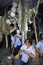 Snow Leopard (Uncia uncia) pelts sold in market with police and shopkeeper in stall, Kashgar, Xinjiang, China