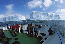 Tourists viewing large tabular icebergs from the deck of a boat, Southern Ocean, Antarctica