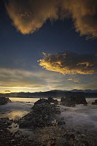 Sunset over limestone rocks by sea, winter snow on Kaikoura Range, Kaikoura, New Zealand