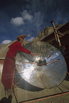 Monk boiling water with solar reflector, Lingshet Monastery, Ladakh, northwest India