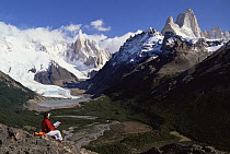 Trekker views Cerro Torre left and Mount Fitzroy from hill above Chalten Village, Patagonia, Argentina