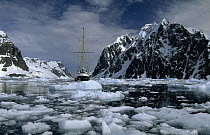 Sailboat avoiding broken ice, Mt Cloos of the Antarctic Peninsula on the left and Wandel Peak of Booth Island on the right, Lemaire Channel, Antarctica
