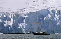 Sailboat dwarfed by glacier, Lemaire Channel, Antarctica