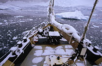 Snow-covered sailboat nearing Couverville Island, Gerlache Strait, Antarctica