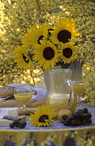 Still-life of sunflowers in vase, fruit, bread, and lemonade