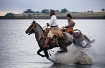 Horsemen riding through shallow water, southern Brazil
