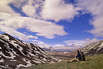Alaska Range in spring snow, photographer resting in valley below mountains, Denali National Park and Preserve, Alaska