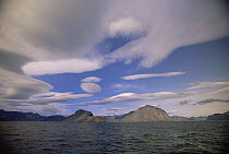 Granite mountain beneath lenticular clouds, surrounding Eclipse Harbor and Torngat Mountain, site of proposed national park, summer, Labrador Sea, Labrador, Newfoundland, Canada