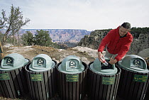 Tourist depositing plastic bottle into recycling garbage cans in parking lot, South Rim, Grand Canyon National Park, Arizona