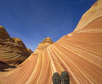 Woman hiker's tired feet in dusty boots against backdrop of sandstone buttes, autumn noon, Paria Wilderness Area, Arizona