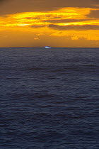 Blue Flash, rare optical phenomenon of refraction of light spectrum when air is clear, briefly visible on horizon of Pacific Ocean at sunset, winter, South Island, New Zealand