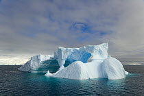 Iceberg with arches and turrets sculpted by waves and melting of ice, Gerlache Passage, Antarctica