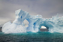 Iceberg with arches and turrets sculpted by waves and melting of ice, Gerlache Passage, Antarctica