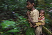 Baka woman gathering fruit and nuts with her baby, Cameroon