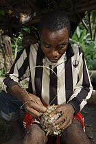 Baka man making a soccer ball from leaves, Cameroon