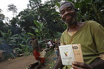 Baka man holding his identification that show that he is the oldest person in the community, Cameroon
