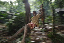 Baka child swinging on liana, Cameroon