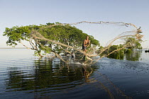 Fisherman throwing net in flooded forest, Rio Negro, Amazonia, Brazil