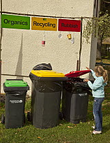 Girl disposes of garbage, recycling, and organic waste into garbage bins, Little River, Banks Peninsula, Canterbury, New Zealand