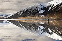Fisherman with reflection in Lake Pearson, Castle Hill Basin, Canterbury, New Zealand