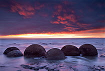 Sunrise over boulders in the surf, Moeraki Beach, South Island, New Zealand